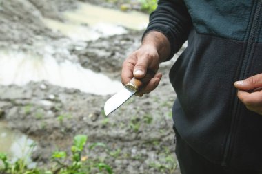 Doğada bıçak tutan beyaz bir adam..