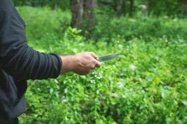 Doğada bıçak tutan beyaz bir adam..