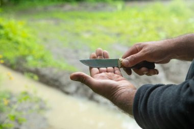 Doğada bıçak tutan beyaz bir adam..