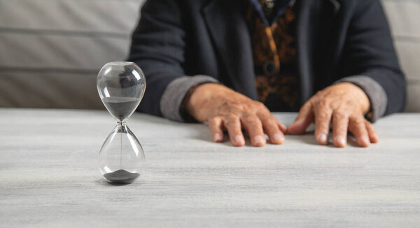 Пожилая женщина руки с песочными часами.