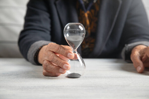 Пожилая женщина руки с песочными часами.