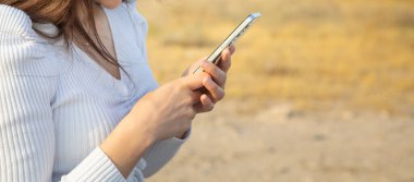 Açık havada cep telefonu kullanan beyaz bir kadın..