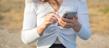 Açık havada cep telefonu kullanan beyaz bir kadın..