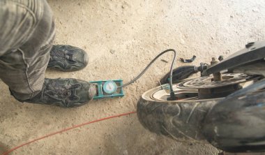 Motosiklet lastiğini hava pompasıyla şişiren adam..