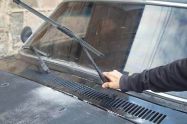 Adam arabanın sileceklerini değiştiriyor..