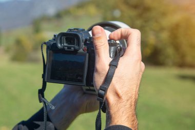 Elinde dijital bir fotoğraf makinesi olan fotoğrafçı doğada fotoğraf çekiyor..