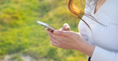 Açık havada cep telefonu kullanan beyaz bir kadın..