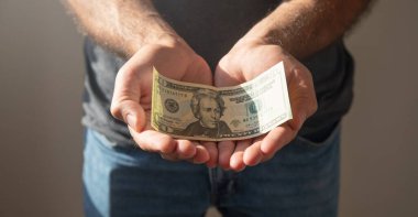 Beyaz adam yırtık dolar banknotu gösteriyor..