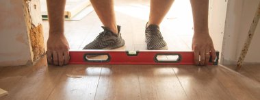 Katları kontrol etmek için ruh seviyesini kullanan işçiler.