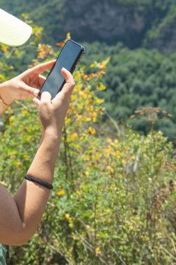 Açık havada cep telefonu kullanan beyaz bir insan..