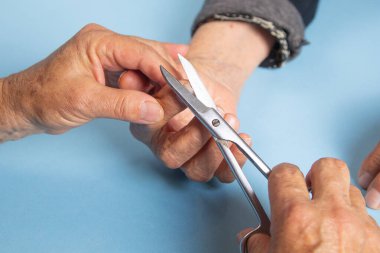 Yaşlı kadının tırnaklarını kesmesine yardım eden kadın..