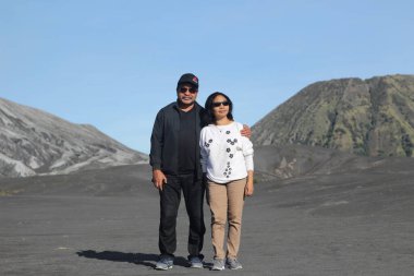 Endonezya 'nın Bromo Dağı' ndaki (Lautan Pasir) uçsuz bucaksız Karadeniz 'de arka planda volkan konisi bulunan Güneydoğu Asyalı yaşlı bir çiftin tam fotoğrafı..