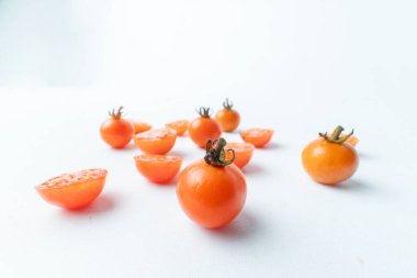 Taze vişneli domatesler, bütün ve dilimlenmiş, temiz beyaz arka plana saçılmış. Bol miktarda fotokopi alanı olan minimalist gıda konsepti. Sağlıklı malzemeler.