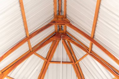 Çatının iç kısmının alçak açılı görüntüsü. Yapı ahşap kirişler (kirişler) ve kıvrımlı teneke tavandan yapılmıştır. Simetrik mimari.