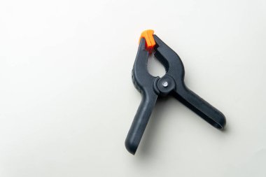 Beyaz arka planda izole edilmiş turuncu uçlu siyah plastik bir yay kıskacı. Ahşap işçiliği, el işi ya da tamirat için bir DIY aracı. Kopyalama alanı.