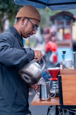 Kahve barmeninin yanına paslanmaz çelik çaydanlıkla kırmızı bir damlaya su dökerek yaklaşın..