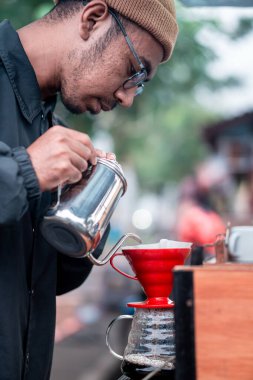 Kahve barmeninin yanına paslanmaz çelik çaydanlıkla kırmızı bir damlaya su dökerek yaklaşın..