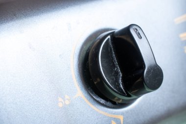 Gri metalik sobanın tepesindeki siyah bir aletin makro görüntüsü günlük mutfak ekipmanları ve ev aletlerini gösteriyor..