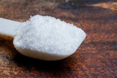 Bir kaşıkta beyaz MSG çeşnili kristallerin aşırı makro pozu, Asya mutfağında ve gıda endüstrisinde yaygın bir lezzet artırıcı..