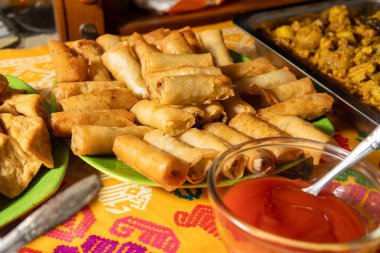 Çeşitli geleneksel Endonezya usulü kızarmış atıştırmalıkların yakın çekimi. Yumurta ruloları, kızarmış tofu ve Tempeh de dahil. Renkli bir masa örtüsü üzerinde baharatlı sambal biber sosu ile servis ediliyor..