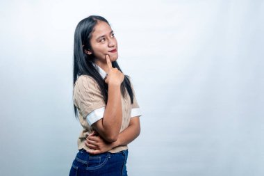 Endonezyalı genç bir kadının portresi. Çenesini tutuyor ve yukarı bakıyor. Beyaz arka planda düşünme, planlama ve vizyonu temsil ediyor..