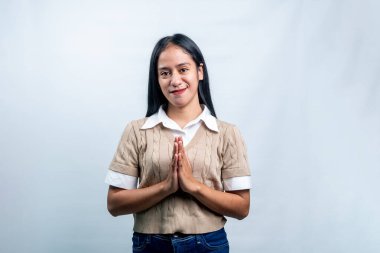 Genç Endonezyalı bir kadın gülümseyerek ve el ele tutuşarak geleneksel bir selamlama ya da dua jesti yapıyor. Hoş geldin ya da dini temalar için mükemmel.