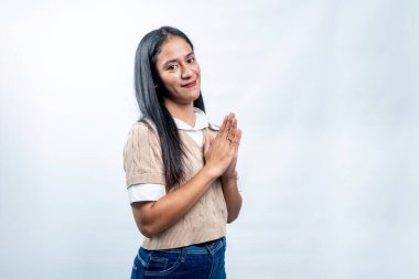 Geleneksel bir selamlama ya da dua jesti ile elleri bir arada olan Endonezyalı genç bir kadın. Saygı, minnettarlık ve beyaz arka planda hoş geldiniz..