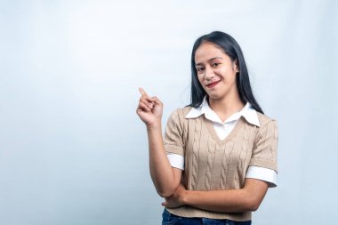 Kahverengi kazaklı mutlu bir Endonezyalı kadın boş bir yeri işaret ediyor. Reklamlar, ürün yerleştirme ve duyurular için ideal..