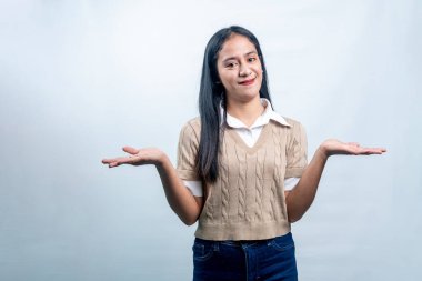 Mutlu bir Endonezyalı kadın ellerini yana uzatarak iki seçenek sunuyor ya da temiz beyaz bir arkaplanda denge seçenekleri sunuyor..