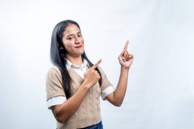 Mutlu genç Endonezyalı bir kadın parmaklarını yukarı ve yana kaldırarak metin, reklam ve ürün yerleştirme için boş bir alan sunuyor..