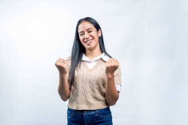 Mutlu, genç Endonezyalı bir kadın sevinçle gülümserken yumruklarını sıkar, heyecan, başarı ve kazanma ruhunu ifade eder..