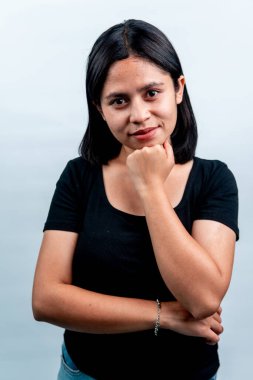 Güzel bir Asyalı kadının portresi. Eli çenesinde gülümsüyor. Stüdyoda beyaz bir arkaplanda poz veriyor..