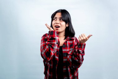 Heyecanlı Endonezyalı kadın beyaz arka planda izole edilmiş, şok olmuş bir ifadeyle boş bir alanı işaret ediyor..