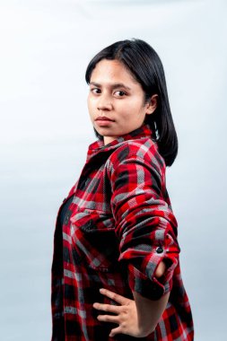 Kırmızı kareli gömlek giyen, cesur ve ciddi bir ifadeyle kameraya bakan Güneydoğu Asyalı genç bir kadının yan bakış açısı..
