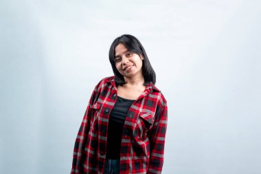 Kameraya gülümseyen kendine güvenen genç bir Güneydoğu Asyalı kadın, temiz bir stüdyo arka planına karşı günlük kırmızı bir fanila giyiyor..