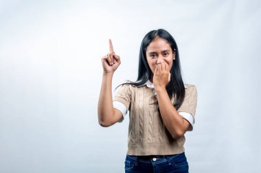 Süveter giymiş genç bir Güneydoğu Asyalı kadının portresi utangaç ya da şaşırmış bir ifadeyi işaret ediyor. Stüdyo çekimi beyaz arkaplanda izole edildi.