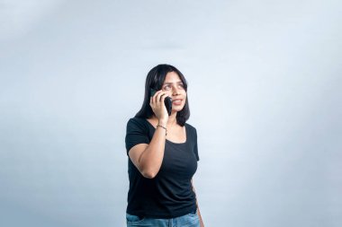 Genç bir Güneydoğu Asyalı kadının mutlu bir telefon konuşması yaparken çekilmiş bir portresi. Açık gri arkaplanda temiz bir atış izole edildi.