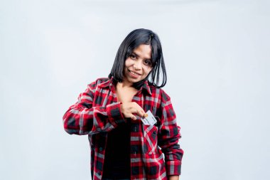 Kırmızı flanel gömlekli gülümseyen Güneydoğu Asyalı kadın cebinde beyaz bir kredi kartı taşıyor, temiz beyaz bir arka planda izole edilmiş..