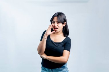 Genç Güneydoğu Asyalı kadın el ele fısıldıyor, bir sırrı paylaşıyor ya da bağırarak haber veriyor. Temiz beyaz arkaplanda stüdyo portresi.