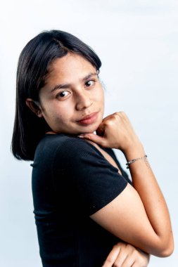 Genç Güneydoğu Asyalı bir kadının portresi, kısa saçlı, eli çenesinde poz veren, temiz bir stüdyo ışıklandırması ve tarafsız beyaz bir arka planı olan.