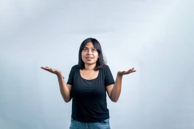 Siyah tişörtlü genç bir Asyalı kadın. Avuç içi açık poz veriyor ve umut dolu bir ifade takınıyor. Yukarı bakıyor, beyaz bir stüdyo arka planında izole edilmiş..