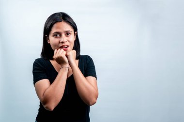 Siyah tişörtlü Güneydoğu Asyalı kadın endişeli bir ifadeyle kameraya bakıyor. İzole stüdyo görüntüleri beyaz, sürpriz ya da korku konsepti.