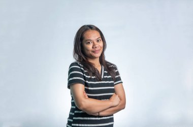 Kollarını kavuşturup poz veren Endonezyalı genç bir kadının portresi ve tarafsız, kendinden emin bir ifade. Yaşam tarzı kullanımı için beyaz arkaplanda izole.