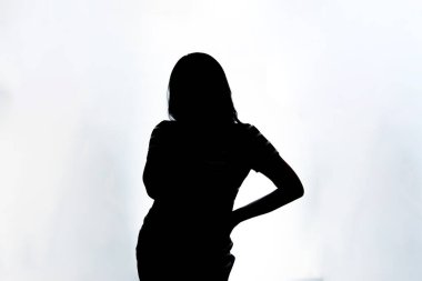 Düşünceli Endonezyalı bir kadının arka ışıklandırmalı silueti. Beyaz arkaplanda yüksek kontrastlı profil çekimi, kavramsal ve sanatsal tasarım için mükemmel.