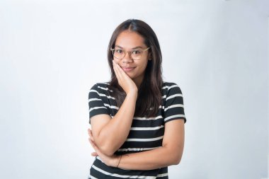 Gözlük takan mutlu Endonezyalı bir kadının portresi. Elleri yanağında poz veriyor. Yaşam tarzı ve eğitim için beyaz arka planda izole edilmiş.