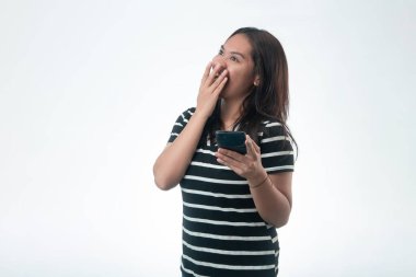 Siyah çizgili tişörtlü neşeli bir Endonezyalı kadın gülüyor ve başka tarafa bakıyor. Elinde bir telefon var..