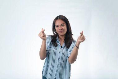 Çizgili tişörtlü mutlu bir Endonezyalı kadın parmaklarıyla küçük kalp işaretleri yapıyor. Aşk, takdir ve K-pop kültürü kavramı.