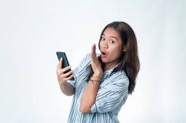 Çizgili tişörtlü genç Endonezyalı bir kadın telefonunu gösterirken fısıldıyor. Gizli anlaşmalar, dedikodu ya da özel haber kavramı.