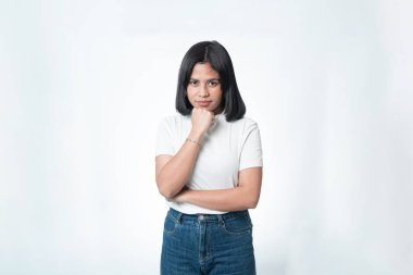 Beyaz tişörtlü Endonezyalı kadın portresi, elleri çenesinde poz veriyor. Ciddi düşünceli bir ifade. Beyazda izole edilmiş.