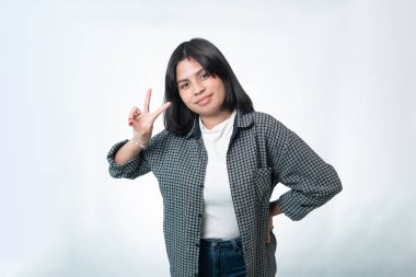 Mutlu Endonezyalı bir kadının V işareti ya da barış işareti yapan portresi. Temiz beyaz arka planda ekose gömlekli sıradan bir fotoğraf..